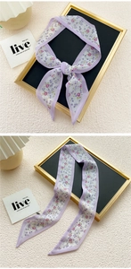 Detail of a slim purple floral silk scarf used as a hair tie or bag handle wrap