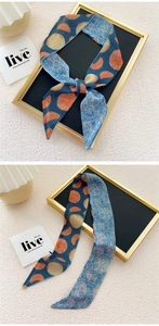 Detail of narrow silk scarf featuring orange slices and fruit illustrations on blue fabric