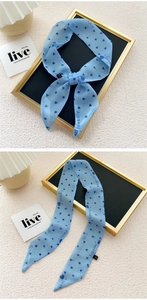 Detail of light blue narrow scarf with heart print and stylish knot on table