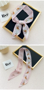 Macro detail of a pink floral skinny scarf showing intricate flower patterns and texture
