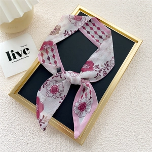 Pink floral and purple checkered skinny twilly silk scarf tied in a bow on a black board