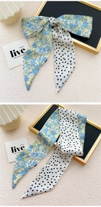 Detail van zijden sjaal met bloemen en stippen als strik voor haar- of halsstyling