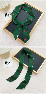 Détail d'un foulard en soie vert foncé à pois attaché sur un plateau de luxe chic