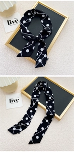 Détail d'un élégant foulard Twilly noir à pois blancs noué avec raffinement