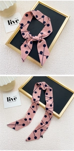 Vue détaillée d'un foulard en soie rose à motifs géométriques noué en nœud élégant