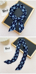 Détail d'un foulard étroit bleu marine à motifs géométriques noué en un nœud
