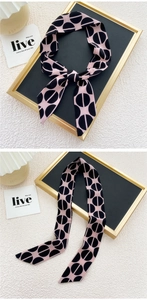 Détail d'un foulard twilly rose et noir à motif géométrique avec texture satinée