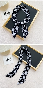 Détail d'un foulard en soie rétro étroit avec motif géométrique noir et blanc noué en nœud