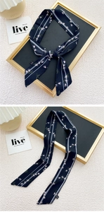 Détail de l'étiquette 100% polyester et motif floral bleu marine sur l'écharpe mince