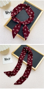 Détail d'un long foulard en soie bordeaux avec motif de feuilles blanches en polyester