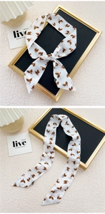 Détail d'un foulard étroit en soie blanche avec imprimé feuilles brunes pour sac