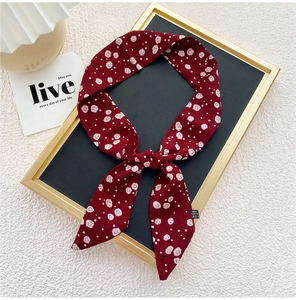 Détail d'un foulard étroit rouge à motif floral en polyester, présenté comme un bandeau