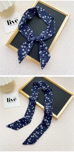 Détail d'un foulard en soie bleu marine à motif pissenlit noué sur un cadre doré
