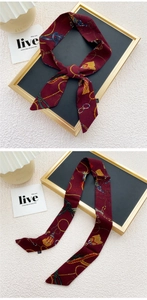 Détail d'un foulard en soie bordeaux avec motif de chaîne dorée, noué et plat