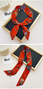 Gros plan d'un foulard en soie orange avec des motifs de cordes nautiques et de blasons dorés