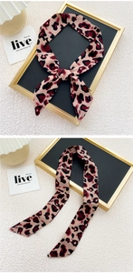 Détail d'un foulard en soie léopard noué en ruban à côté d'une lampe de bureau