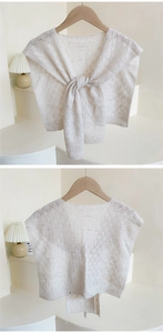 Close-up of white crochet hollow knit shawl with elegant knot design and diamond patterns