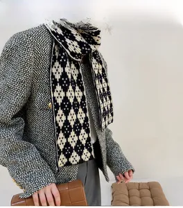 Detail view of a knitted scarf with black and white diamond pattern in British retro style