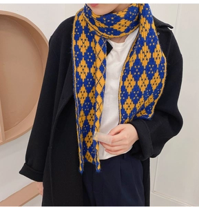 Detail of yellow and blue argyle knit scarf with thick texture on black coat