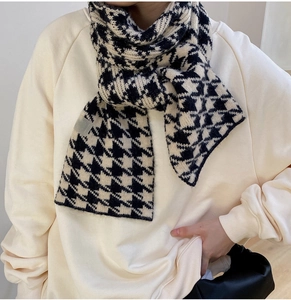 Close-up of a thick black and white houndstooth knit scarf with soft wool texture
