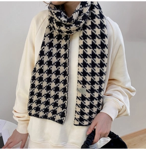 Close-up of thick knitted scarf featuring a classic black and white houndstooth pattern