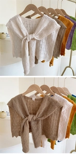 Detail of hollow-out knit shawl with delicate wavy edges and a self-tie knot design