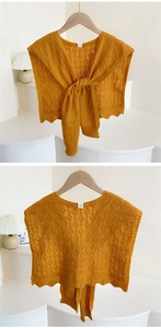 Close-up of ginger yellow knit shawl with hollow out crochet and wavy edge detail