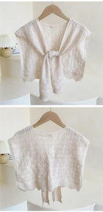 Detail of cream knit shawl featuring geometric hollow patterns and front tie design
