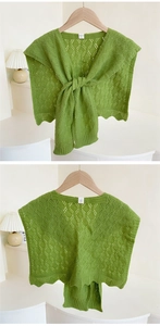 Macro detail of grass green knit shawl showing hollow diamond patterns and wavy scalloped edges