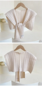 Detail of cream cable knit shoulder wrap showing intricate weave and wavy edge texture