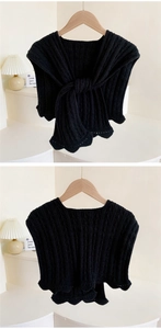 Detail of black ribbed knit shawl featuring intricate scalloped lace edges and a bow tie knot