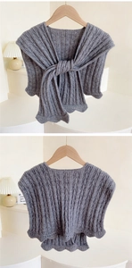 Detail of grey cable-knit shawl with elegant scalloped edges and knotted tie design