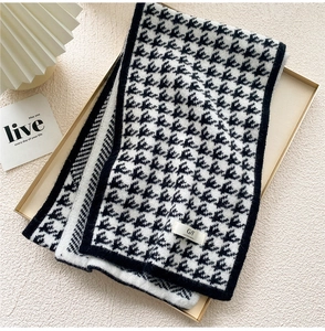 Close-up of thick knitted houndstooth scarf with elegant woven label on a stylist tray