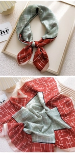 Detail of a square silk scarf with red-brown and green patchwork and white grid pattern