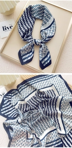 Detailed view of square silk scarf featuring blue geometric patterns and satin texture