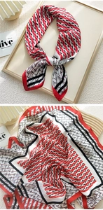 Detail of a red, black, and white silk-like scarf with geometric letter patterns