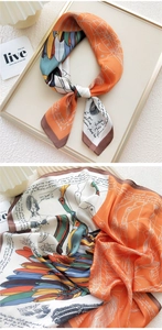 Macro detail of silk square scarf featuring orange pegasus print and hand-written script