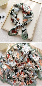 Detailed view of square silk scarf with cartoon cat prints and dark green borders