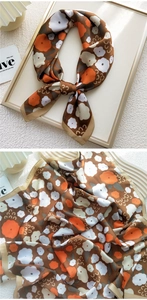Detail of silk-texture square scarf with orange floral prints on a dark brown base
