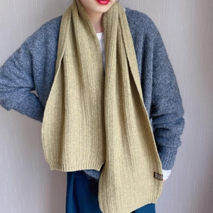 Detail of olive green ribbed knit scarf showing texture and small brown woven label
