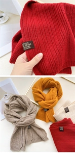 Macro detail of ribbed knit scarves with brand labels in dark red, yellow, and beige