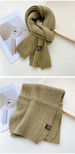 Detailed macro view of olive green knit scarf showing thick ribbed texture and brand patch