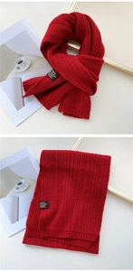Close-up of deep red knitted scarf featuring vertical rib patterns and a small fabric tag