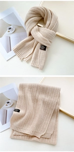 Detail of oat beige cable knit scarf featuring a stylish black woven brand label