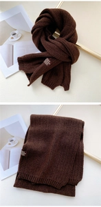 Close-up of coffee brown chunky knit scarf with woven brand label and rib texture
