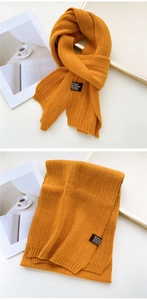 Detail of ginger yellow knitted scarf with ribbed texture and black woven label