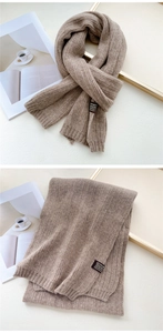 Detailed view of brown chunky knit scarf with black fabric label and soft wool texture