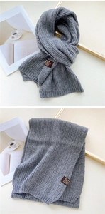 Detail of grey ribbed knit scarf featuring a premium brown leather brand tag detail