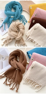 Detailed close-up of thick knit winter scarves with fringes and minimalist logo labels