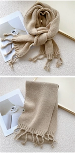 Detail of chunky knit scarf texture with fringe tassels and woven brand label